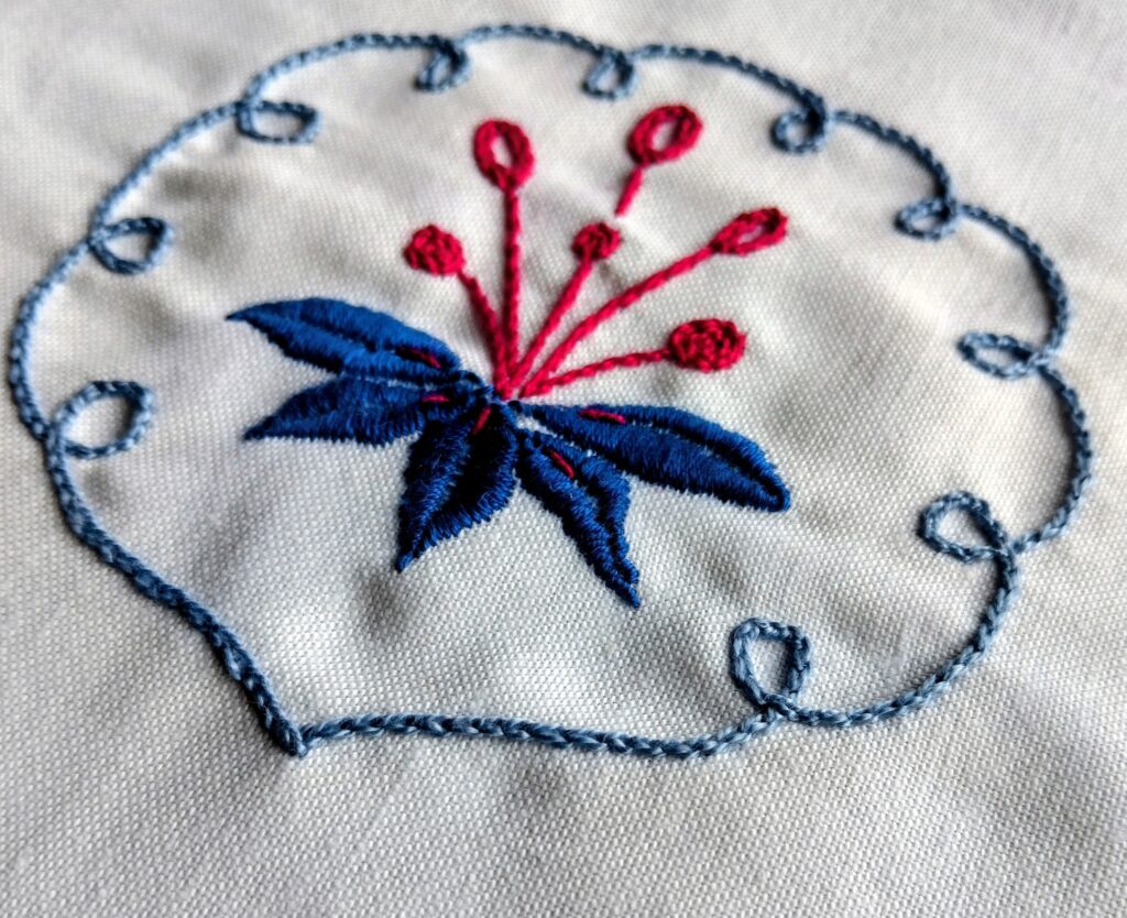Photo of embroidery on a piece of white cloth - a circle with leaves and a flower inside