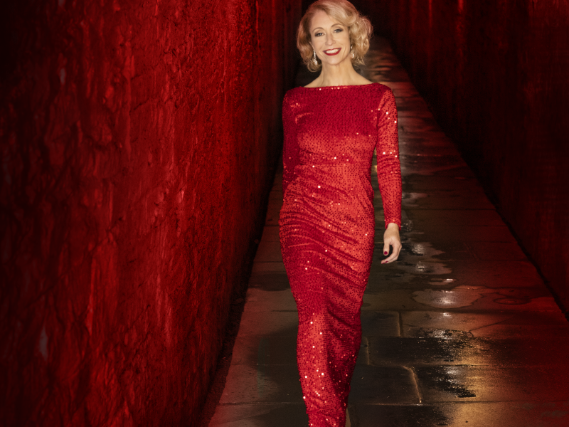 Photo of Deirdre Masterson in a red dress walking down a red lighted corridor