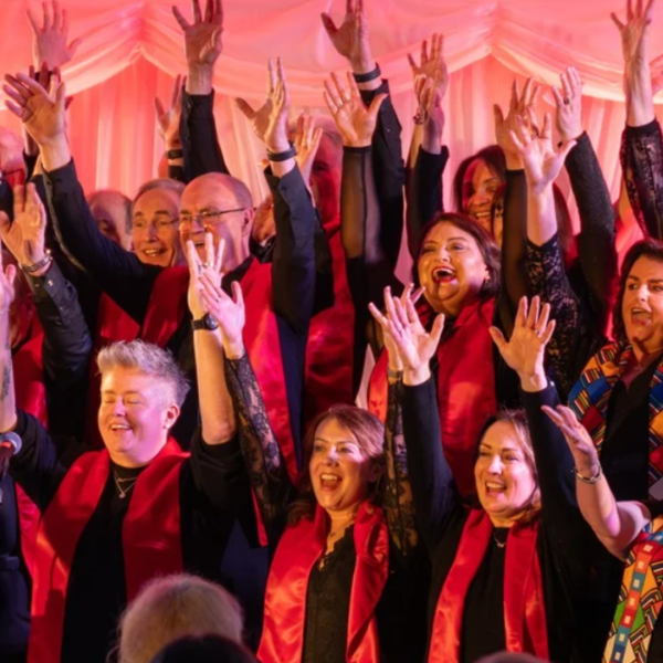 SUSO Choir. People singing holding hands in the air and smiling